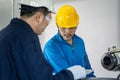 Asian mechanical workers working on milling machine. The technicians wearing protective glasses and helmet when operating the mach