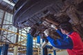 Asian mechanics in uniform are working in auto service with lifted vehicle. Car repair and maintenance in the auto repair center Royalty Free Stock Photo