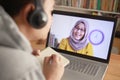 Asian man having video teleconference with a woman on his laptop at home, online learning or working from home