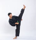 Asian men wearing pencak silat uniforms with green belts kicking one leg up high