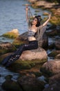 Asian Mermaid With Net At Sea Coast on Rocks While Wearing Seashell Decorated Crown and Black Shiny Tail On Sexy Body Covered With