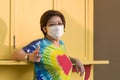 Asian middle aged LGBT woman in rainbow t-shirt with protective mask looking at camera while posing outdoor background