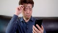 Asian middle-aged male trying to read something on his mobile phone. presbyopia, myopia.