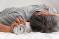 Asian middle-aged man is holding a white alarm clock and his face showed boredom and feeling bad, his problem is a sleep disorder. Royalty Free Stock Photo