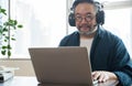 Asian middle aged man sitting at home working on video call. Work from home concept. Royalty Free Stock Photo