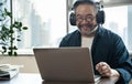 Asian middle aged man sitting at home working on video call. Work from home concept. Royalty Free Stock Photo