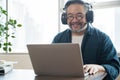 Asian middle aged man sitting at home working on video call. Work from home concept. Royalty Free Stock Photo