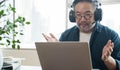 Asian middle aged man sitting at home working on video call. Work from home concept. Royalty Free Stock Photo