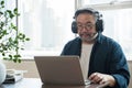 Asian middle aged man sitting at home working on video call. Work from home concept. Royalty Free Stock Photo