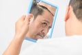 Asian middle-aged man was looking in the mirror and worry about hair loss or hair gray Royalty Free Stock Photo