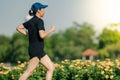 Asian middle-aged woman wearing a black dress, blue hat, running stretching in park near to lake. Get the sun light in the morning Royalty Free Stock Photo