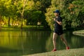 Asian middle-aged woman wearing a black dress, blue hat, running stretching in park near to lake. Get the sun light in the morning Royalty Free Stock Photo