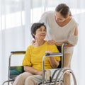 Asian middle-aged woman take carre and help older famale patient on a wheelchair with smile happy face