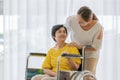 Asian middle-aged woman take carre and help older famale patient on a wheelchair with smile happy face