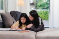 Asian middle-aged woman teach her daughter do homework and drawing at home. Lifestyle mother and kid happy fun spend time together Royalty Free Stock Photo