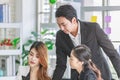 Asian millennial professional successful male businessman mentor in black formal suit standing helping two female employee sitting Royalty Free Stock Photo