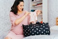 Asian mixed Caucasian pregnant woman packing clothes into a bag for expacting baby to be born