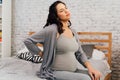 Asian mixed Caucasian pregnant woman suffering back pain sits on bed at home. Royalty Free Stock Photo