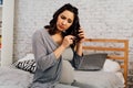 Asian mixed Caucasian pregnant woman suffering from hair loss problem sits on bed at home.