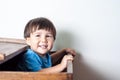 Asian, mixed race toddler boy peeking out or a wooden toy box