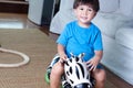 Asian, mixed race toddler boy sitting on a zebra rideon