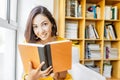 Mixed race woman reading book in library, education and lifestyle concept Royalty Free Stock Photo