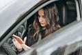 asian or mixed race woman sitting in a car and texting to a friend on a smartphone. car driving safety. communication Royalty Free Stock Photo