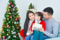 Asian mom and dad opening gift box with her daughter. Near the Christmas tree at home Royalty Free Stock Photo