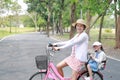 Asian mom and daughter riding bicycle together in park. Happy family Royalty Free Stock Photo