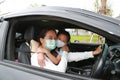 Asian mom and daughter wears hygiene face mask lying in car with looking through camera during coronavirus covid-19 outbreak