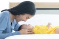 Asian mom seeing and playing with her baby child who is sleep on bed, mom are smiley look happy in the morning in conceptual Royalty Free Stock Photo