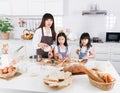 Asian mom and two little daughter wearing apron Cooking Together in the Kitchen Royalty Free Stock Photo