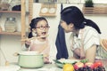 Asian mom woman with daughter cook in kitchen,little girl use spoon to give mom food-big sister and younger sister play cooking in