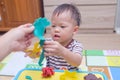 Asian 18 months old toddler boy child having fun playing colorful modeling clay, play dough at home Royalty Free Stock Photo