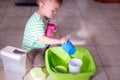 Asian 18 months old toddler boy child having fun pouring water into cup, Wet Pouring Montessori Preschool Practical Life Activitie