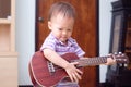 Asian 18 months / 1 year old baby boy child hold & play Hawaiian guitar or ukulele Royalty Free Stock Photo