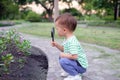 Asian 18 months / 1 year old toddler baby boy child exploring environment by looking through a magnifying glass in sunset at beaut