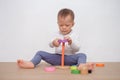 Asian 18 months / 1 year old toddler baby boy child play with colorful wooden pyramid toy / stacking ring toy