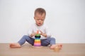 Asian 18 months / 1 year old toddler baby boy child play with colorful wooden pyramid toy / stacking ring toy Royalty Free Stock Photo