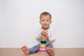 Asian 18 months / 1 year old toddler baby boy child play with colorful wooden pyramid toy / stacking ring toy Royalty Free Stock Photo