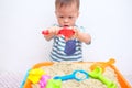 Asian 18 months / 1 year old toddler boy playing with kinetic sand at home ,Fine motor skills development, Montessori education, Royalty Free Stock Photo