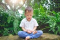 Asian 30 months / 2 years old toddler baby boy child with eyes closed, barefoot practices yoga & meditating outdoors on nature Royalty Free Stock Photo