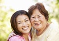 Asian mother and adult daughter head and shoulders outdoors