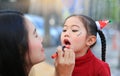 Asian mother applying lipstick over daughter mouth Royalty Free Stock Photo