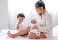 Asian mother carry her newborn baby on lap and sit on bed with her son in the bedroom Royalty Free Stock Photo