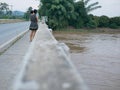 Asian mother carrying her little daughter standing on a bridge showing her little baby a murky muddy river aft Royalty Free Stock Photo