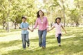 Asian mother and children running hand in hand in park Royalty Free Stock Photo