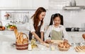 Asian mother and cute daughter, happy young mother teach cook together with small daughter doing bakery and learning to make cake