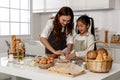 Asian mother and cute daughter, happy young mother teach cook together with small daughter doing bakery and learning to make cake