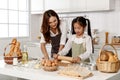 Asian mother and cute daughter, happy young mother teach cook together with small daughter doing bakery and learning to make cake